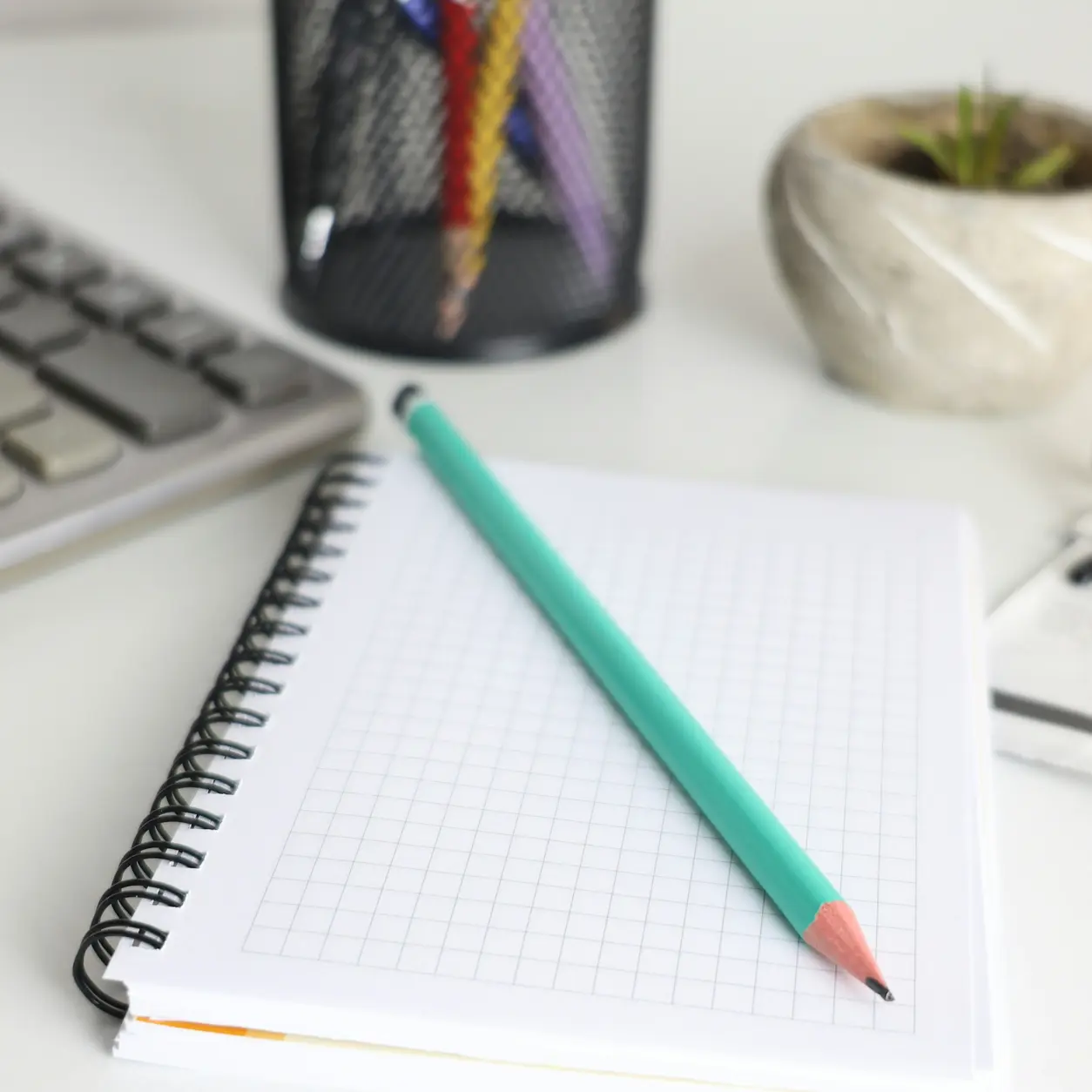 A notebook, pencil and calculator laid out on a desk