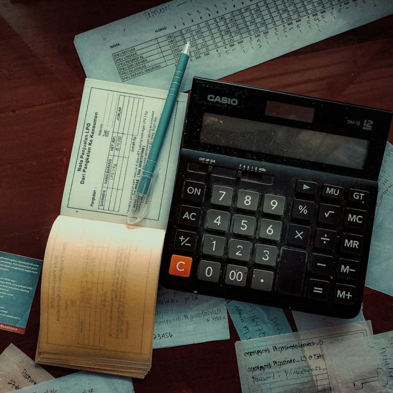 A calculator and neatly gathered bookkeeping records on a desk