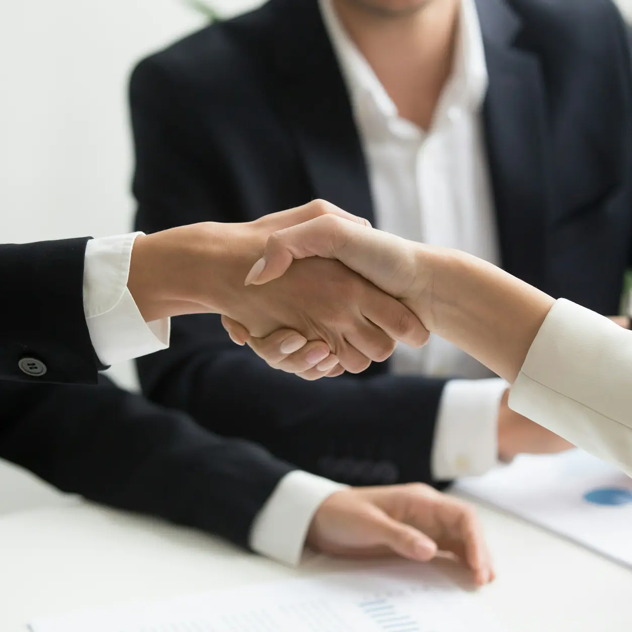 Two people shaking hands over a desk
